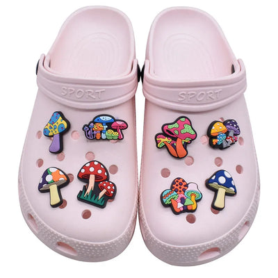 Pink clogs with colorful mushroom-shaped charms on a white background