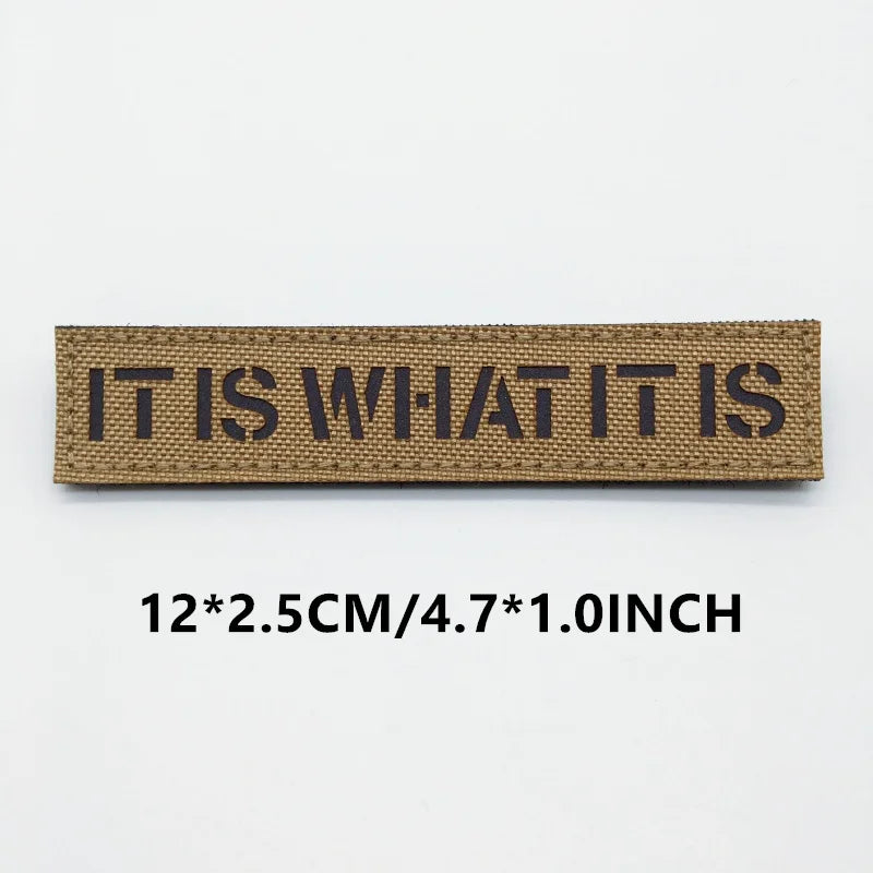 Textile patch with 'IT IS WHAT IT IS' on a white background