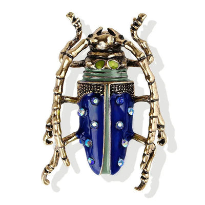 Decorative beetle-shaped brooch with gold and blue design on a white background