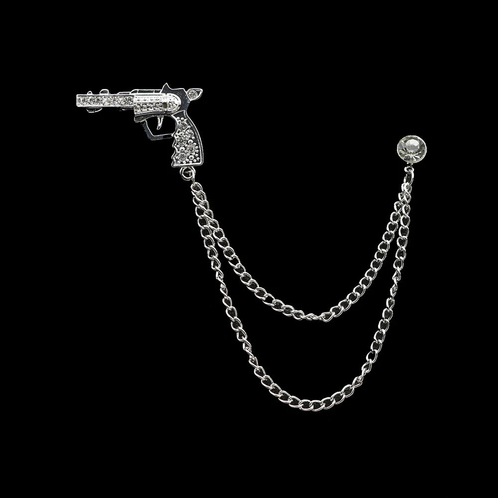 Silver gun-shaped brooch with chain on a black background