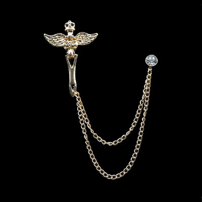 Metallic brooch with chain and gemstone on a black background