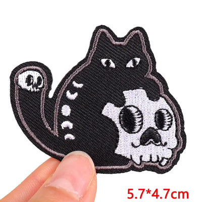 Black cat with skull design patch held by a hand, with size 5.7*4.7cm displayed.