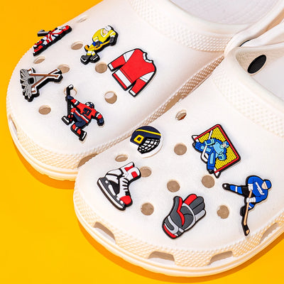 White clogs with colorful shoe charms on a yellow background