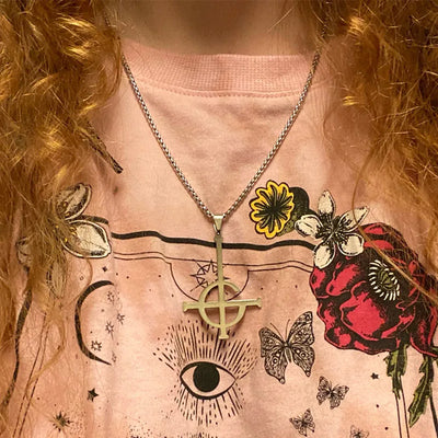 Necklace with a symbol pendant on a person wearing a shirt with floral and eye designs.