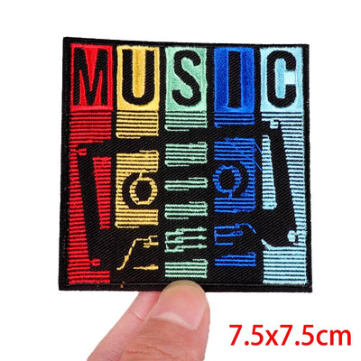 Colorful 'MUSIC' patch held by a thumb with dimensions indicated