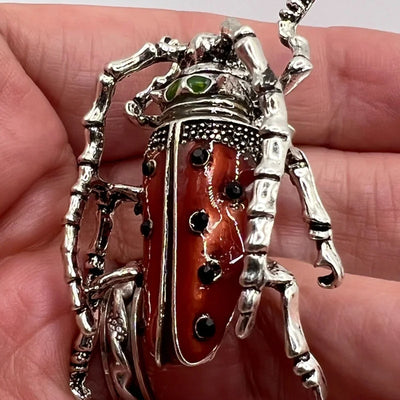Close up of Decorative Red beetle-shaped brooch  held in a hand