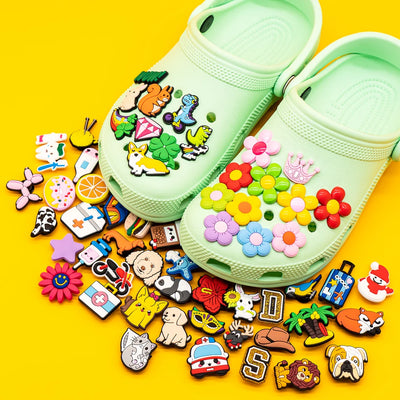 Green clogs with colorful decorative charms on a yellow background