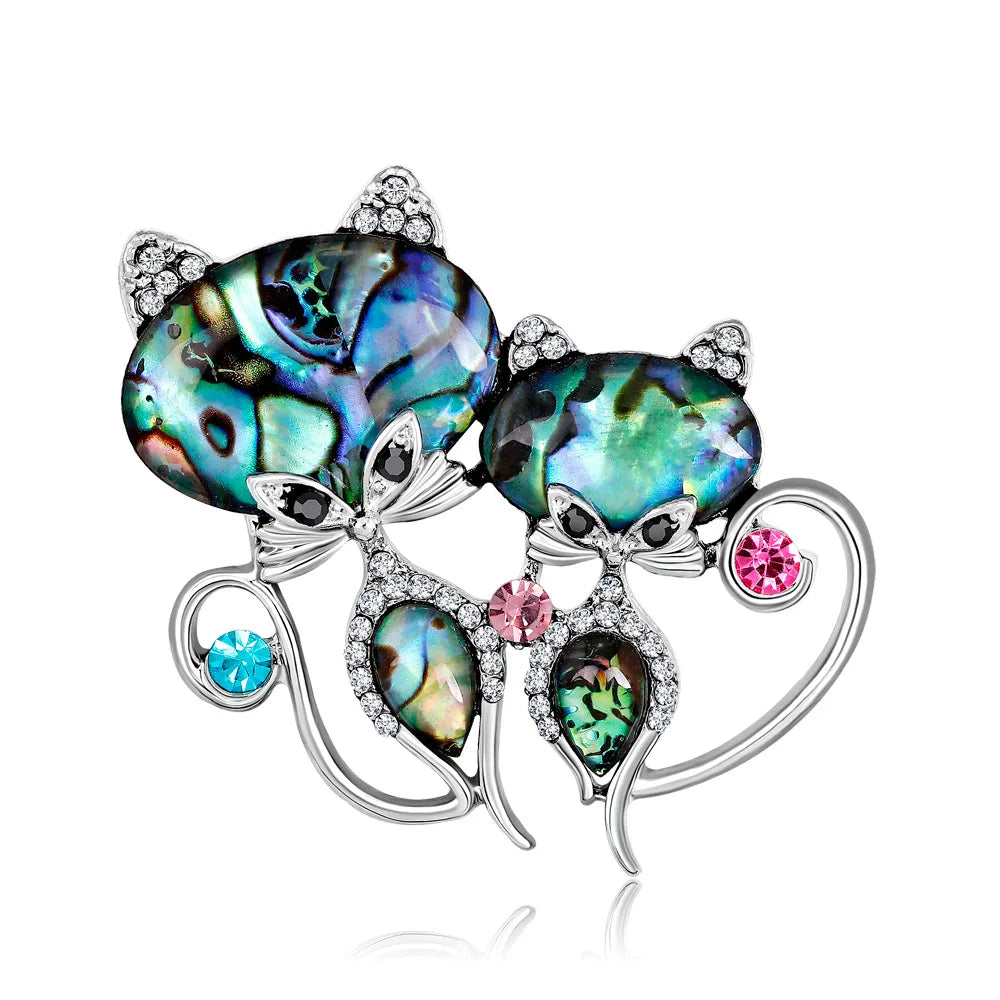 two cats Multicolored gemstone brooch with silver accents on a white background