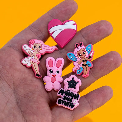 Hand holding colorful cartoon-style pins against a yellow background