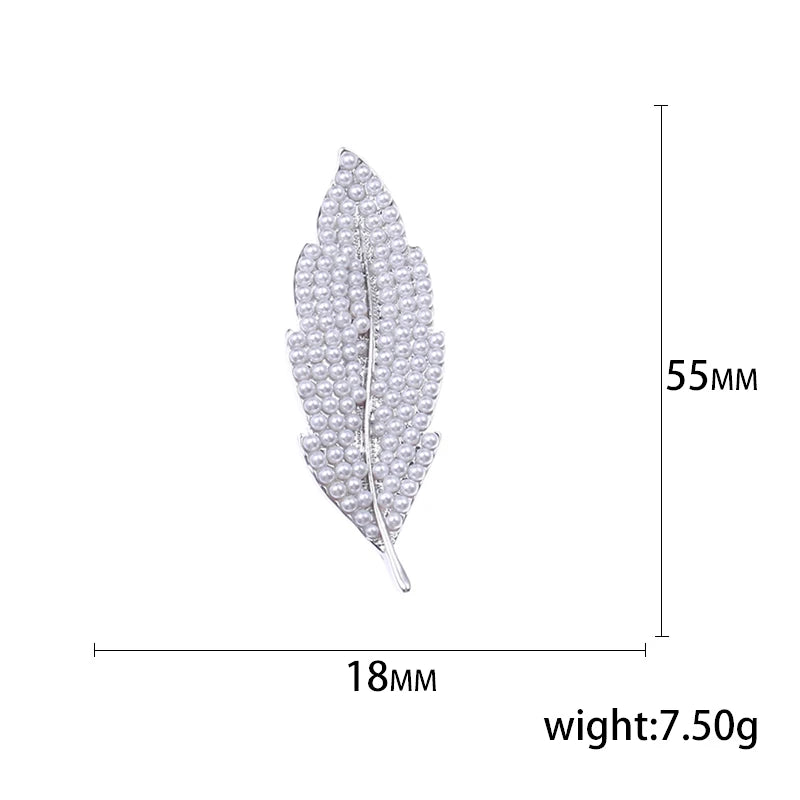 Silver feather-shaped brooch with measurements on a white background