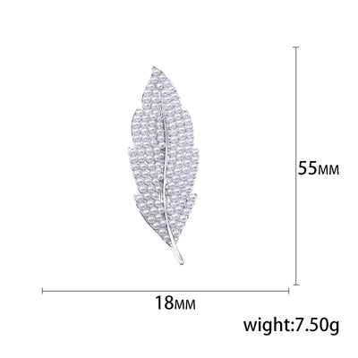 Silver feather-shaped brooch with measurements on a white background