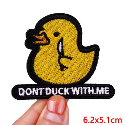 Yellow duck patch with 'Don't Duck With Me' text held by a hand on a white background