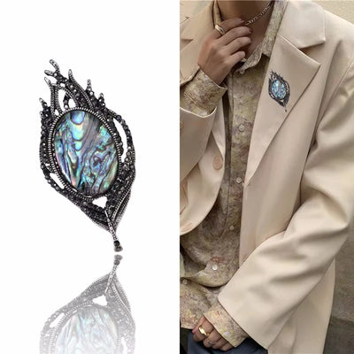 Elegant brooch with gemstone detail on a white background, worn on a beige blazer.