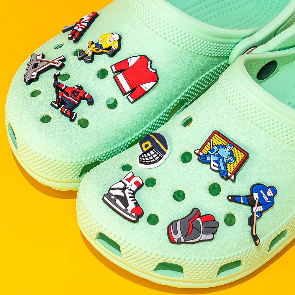 Light green clogs with colorful character pins on a yellow background