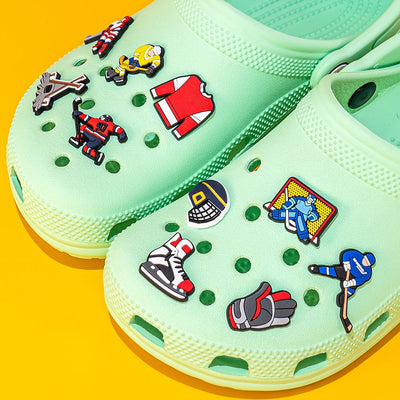 Light green clogs with colorful character pins on a yellow background