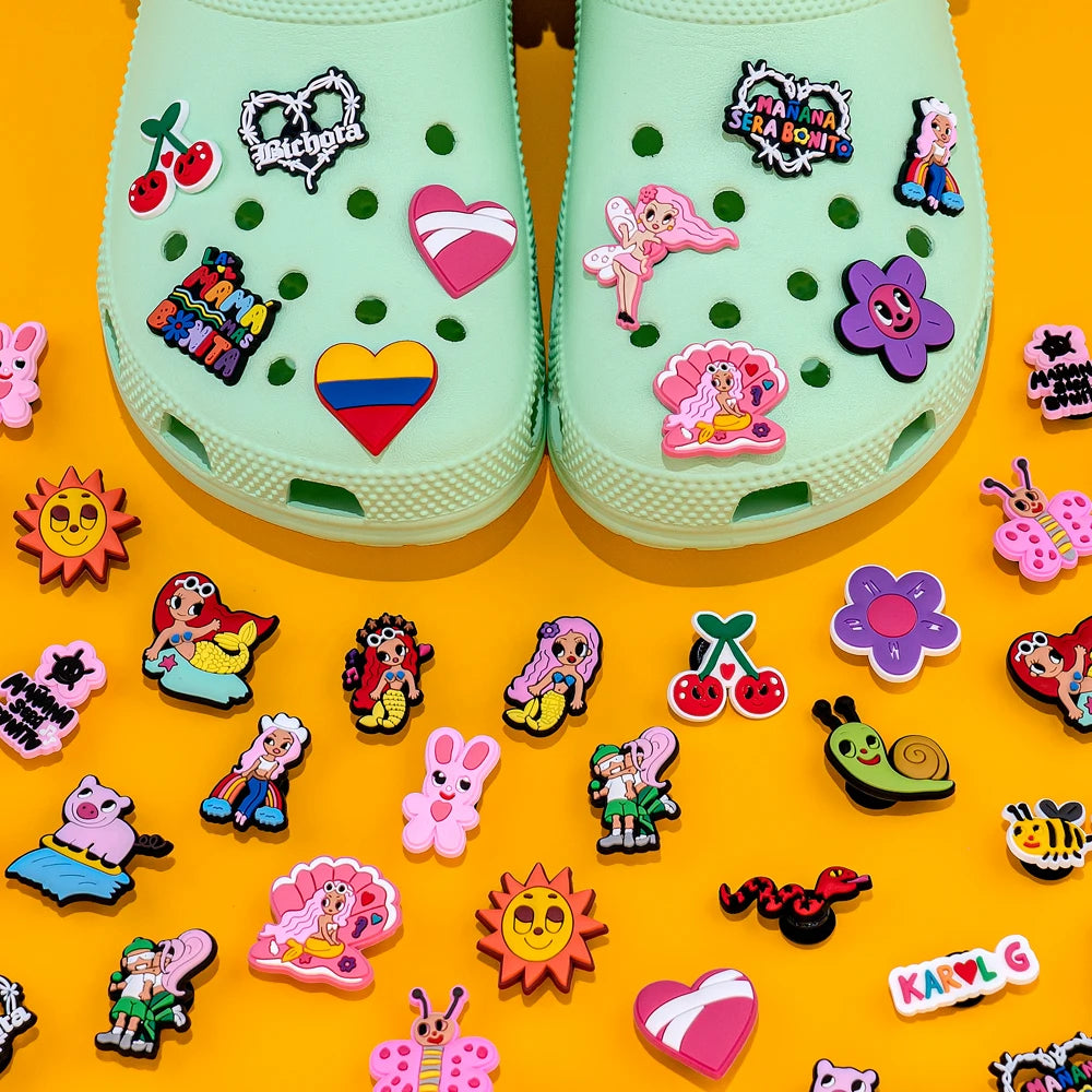 Light green clogs with colorful decorative pins on a yellow background