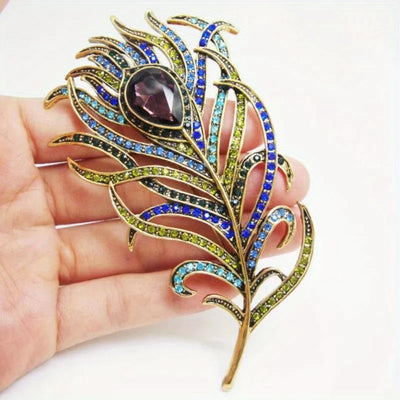 Colorful jeweled brooch held in a hand against a white background