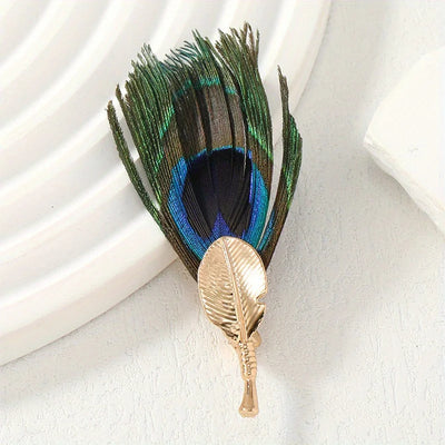 Peacock feather brooch with gold leaf on a white background