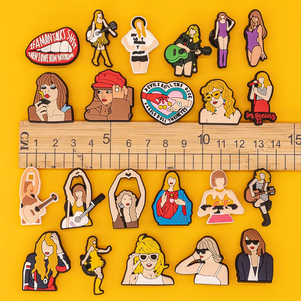 Collection of colorful shoe charms on a yellow background with a ruler for scale.