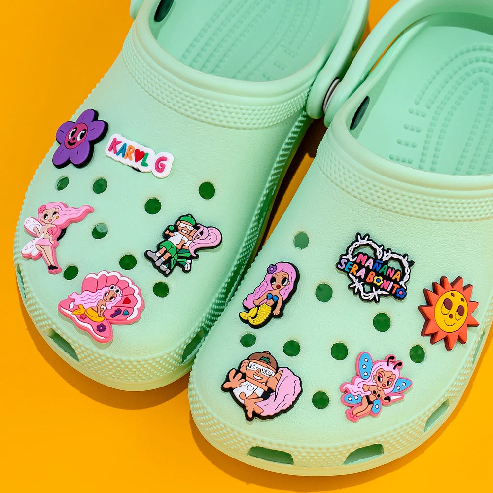 Light green clogs with colorful cartoon character pins on a bright orange background