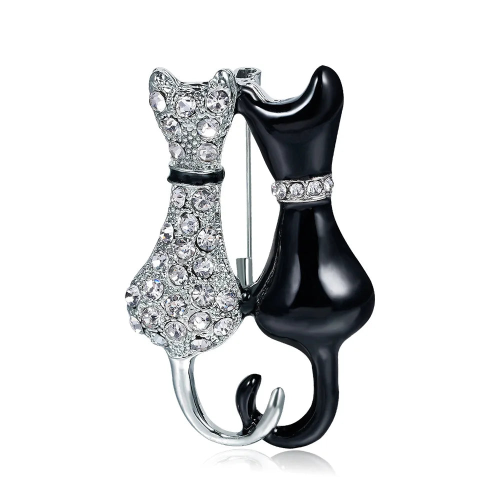 Cat-shaped brooch with one silver and one black body on a white background