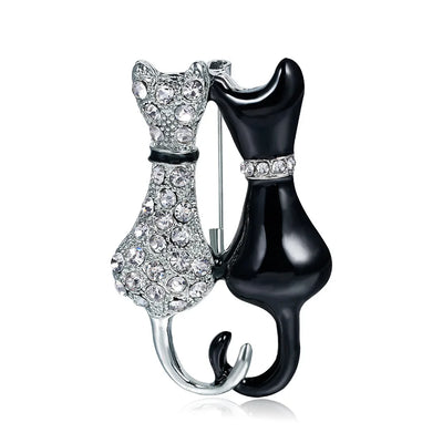 Cat-shaped brooch with one silver and one black body on a white background