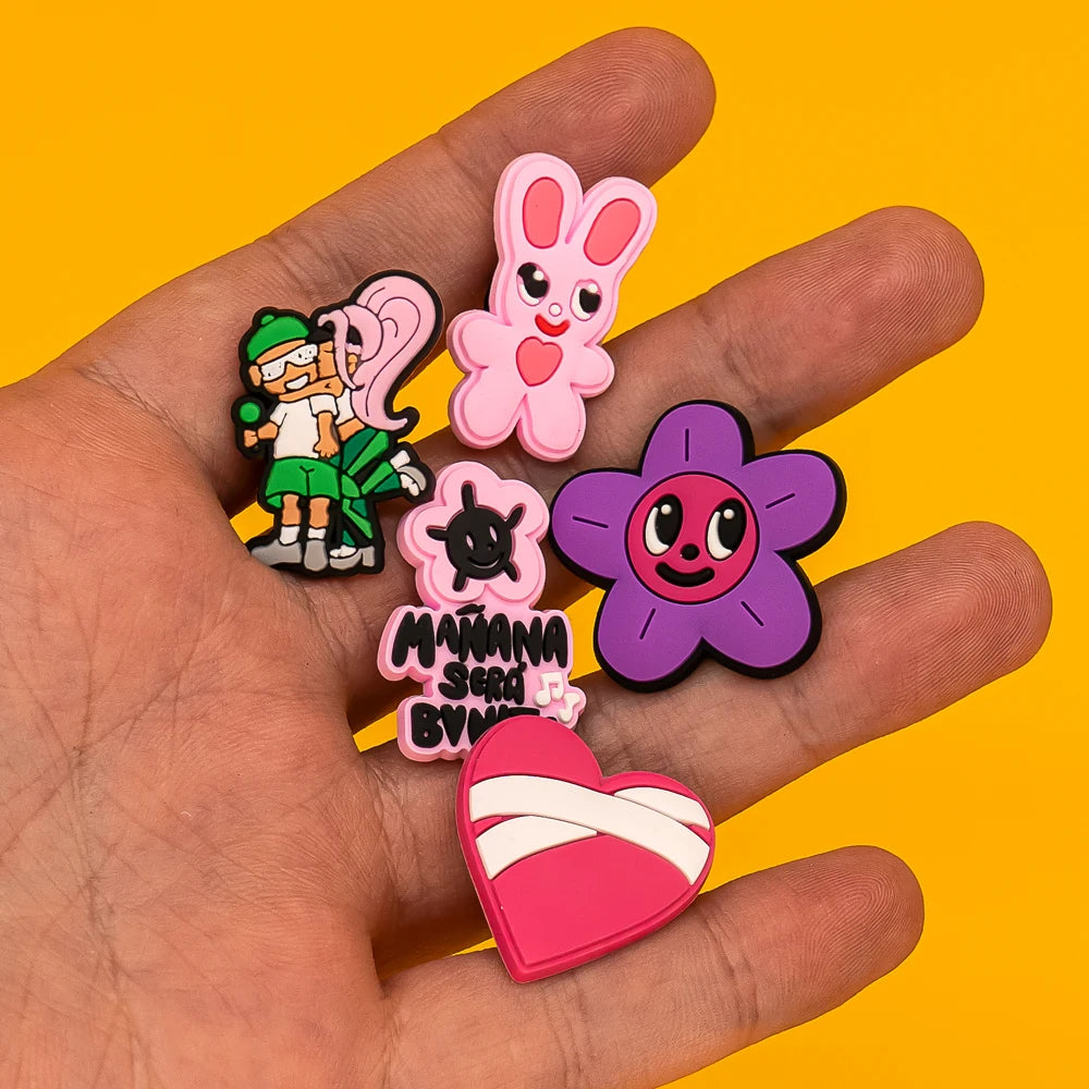 Hand holding colorful cartoon-style shoe charms against a yellow background