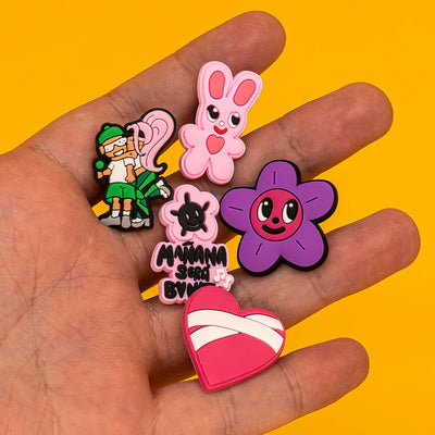Hand holding colorful cartoon-style shoe charms against a yellow background