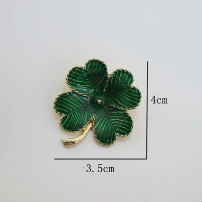 Green four-leaf clover brooch with gold accents on a white background, showing measurements.