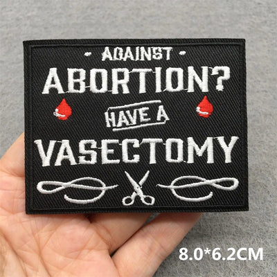 Embroidered patch with text 'Against abortion? Have a vasectomy' held by a hand on a gray background.