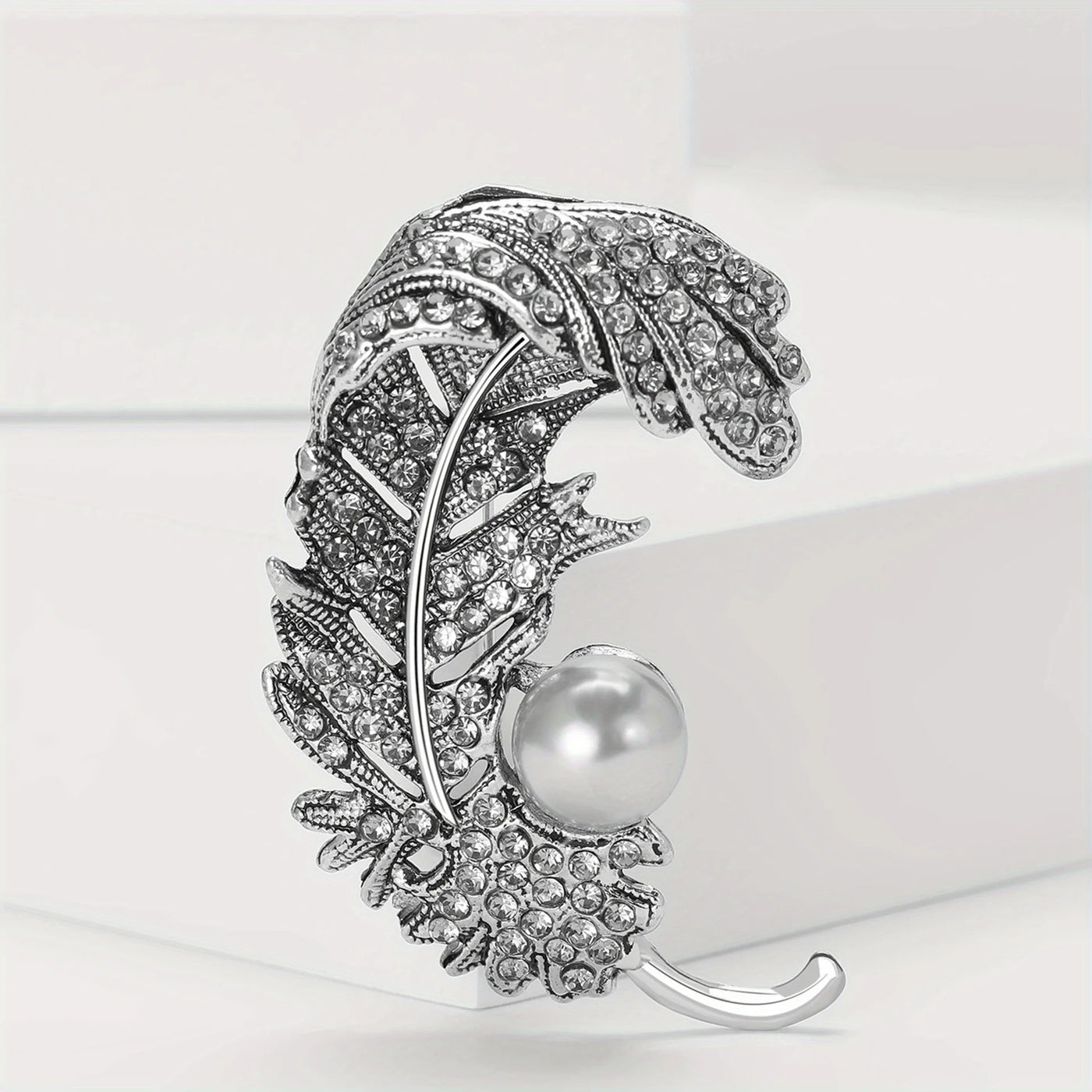 Decorative hair clip with feather design and pearl on a white background