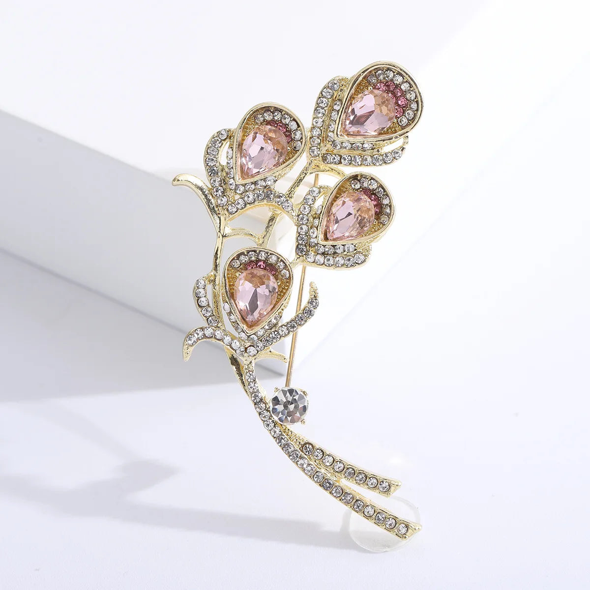 Decorative brooch with pink gemstones and gold accents on a white background