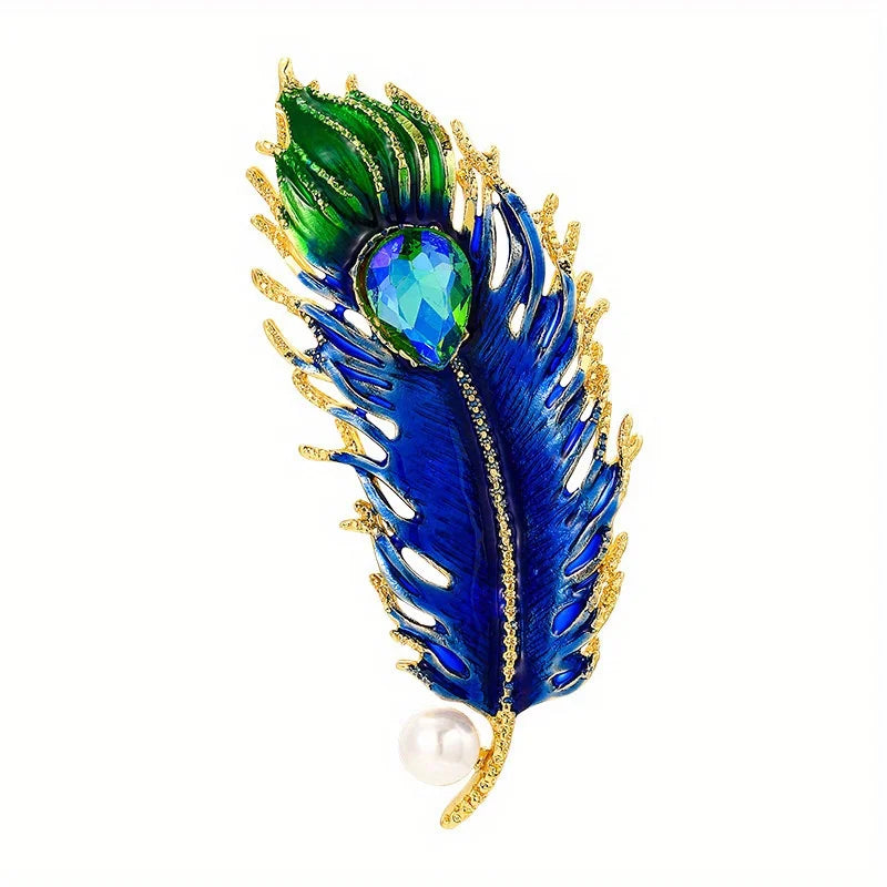 Blue and green peacock feather brooch with gold accents on a white background