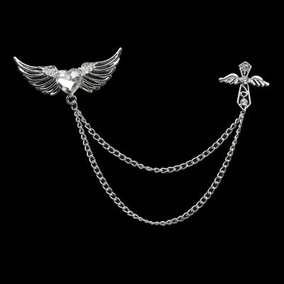 Silver brooch with wings and chain on a black background