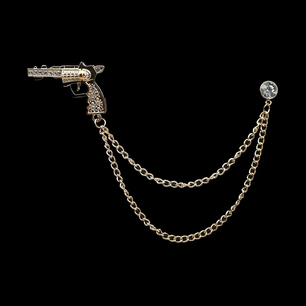 Gold gun-shaped brooch with chain on a black background