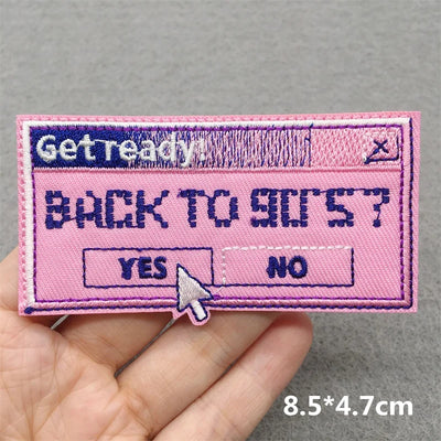 Pink patch with text and design held by a hand on a gray background