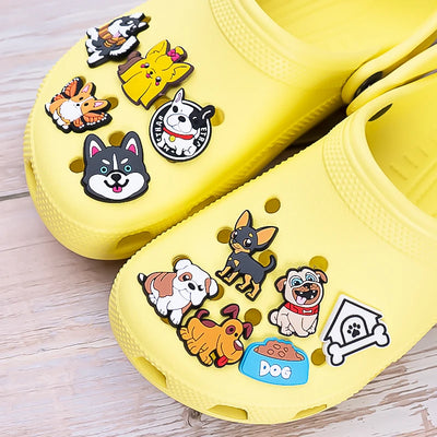 Yellow clogs with various dog-themed charms on a wooden surface