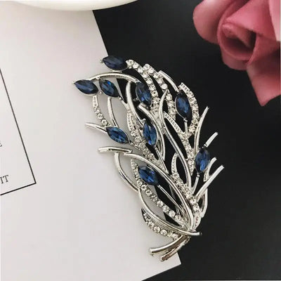 Decorative brooch with blue gemstones and silver detailing on a white background