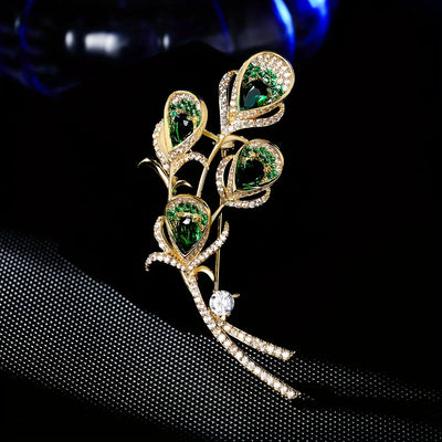Elegant brooch with green gemstones and gold accents on a black background