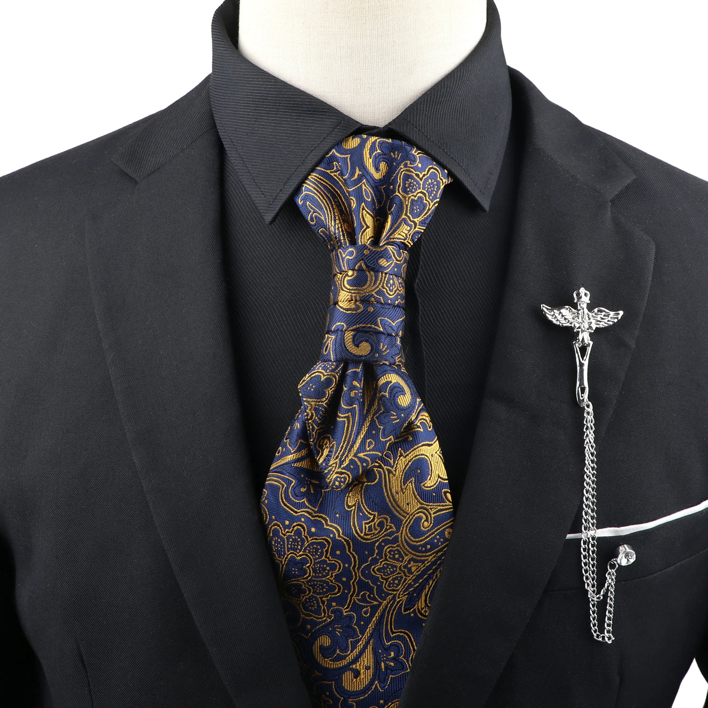 Black suit with a blue and gold paisley tie and a decorative lapel pin on a mannequin.