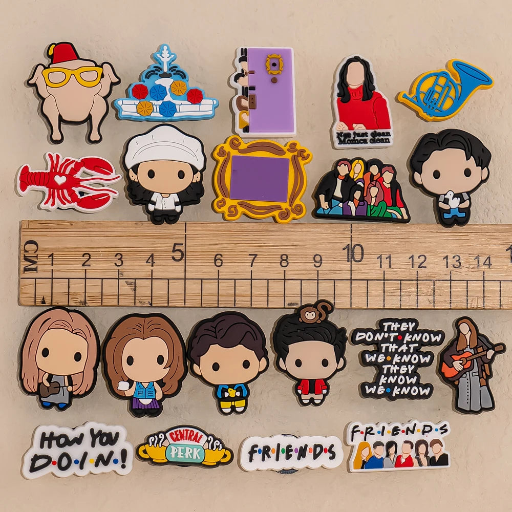 Collection of Friends-themed Shoe charms on a beige background with wooden ruler for scaling