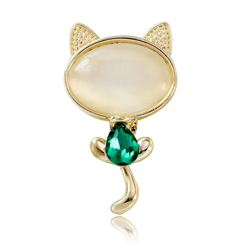 Cat-shaped brooch with gold detailing and a green gemstone on a white background