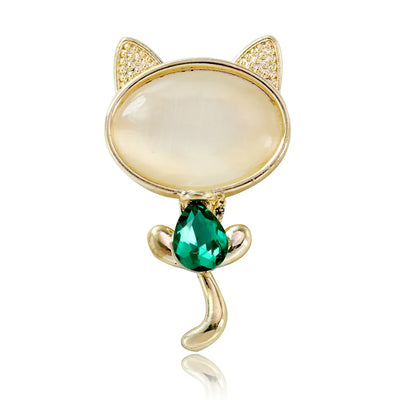 Cat-shaped brooch with gold detailing and a green gemstone on a white background