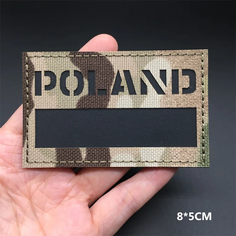 POLAND flag Camouflage patch held in a hand against a dark background