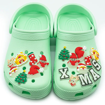 Light green clogs with Christmas-themed shoe charms on a white background