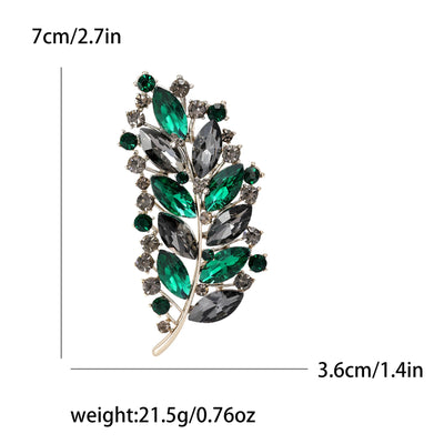 Brooch with green and gray gemstones and measurements on a white background