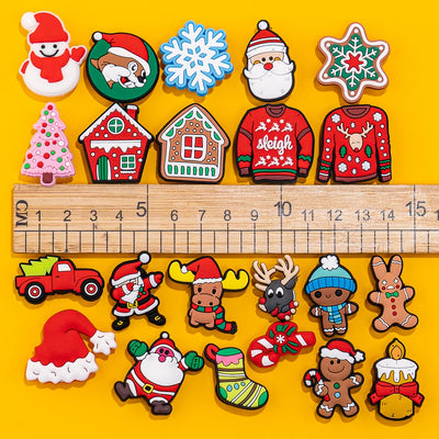 Collection of Christmas-themed shoe charms on a yellow background with a ruler for scale.