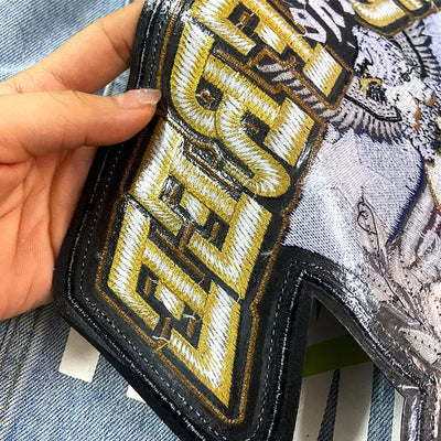 Hand holding a wallet with a gold and black 'BREXIT' patch on a denim background
