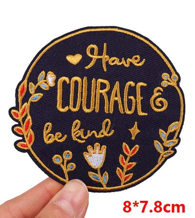 Embroidered patch with 'I have courage & be kind' text held by a hand on a white background.