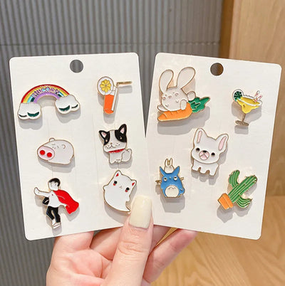 Set of small animal-themed pins on display cards held by a hand.